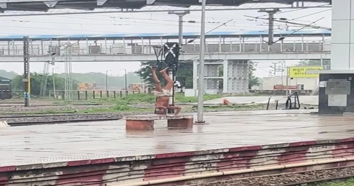 elderly-mans-rainy-yoga-headstand-on-railway-platform-g